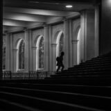 Persoană care urcă treptele unei scări exterioare la răsăritul soarelui, simbol al progresului pas cu pas