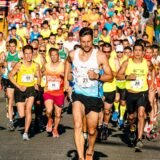 Alergători amatori care participă la o cursă de semimaraton pe o stradă din oraș, într-o dimineață însorită