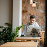 Ziar împăturit lângă o ceașcă de cafea pe o masă de lemn, într-o dimineață liniștită