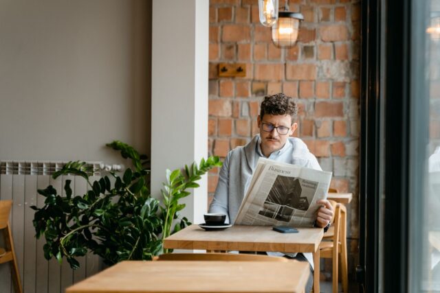 Ziar împăturit lângă o ceașcă de cafea pe o masă de lemn, într-o dimineață liniștită