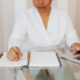 Profesionist care își notează planurile de carieră într-un carnet, la un birou luminos