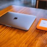 Hard disk extern conectat la un laptop pe un birou, folosit pentru copii de siguranță ale fișierelor