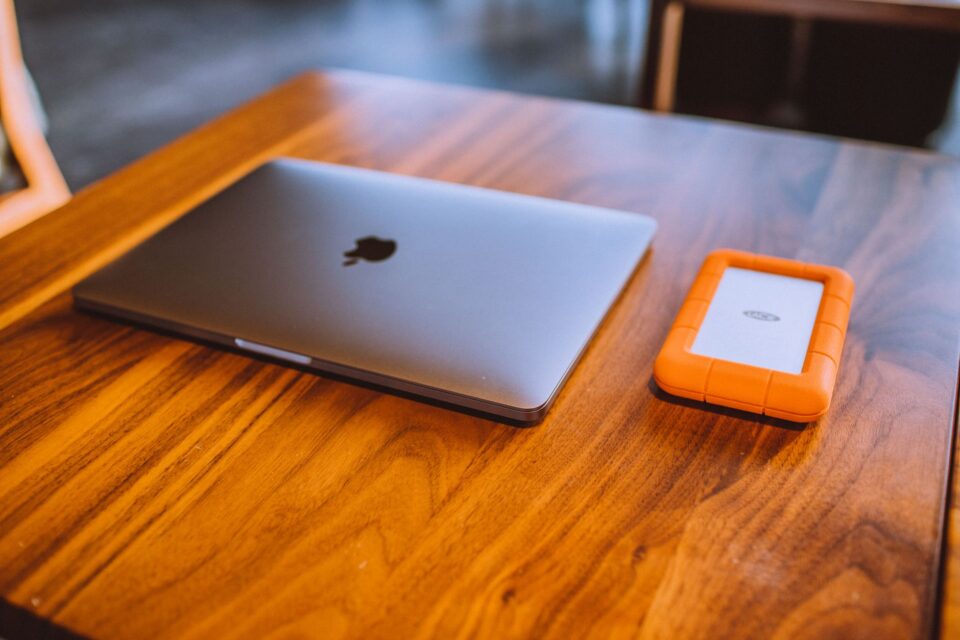 Hard disk extern conectat la un laptop pe un birou, folosit pentru copii de siguranță ale fișierelor